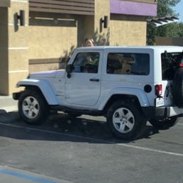 a white jeep parked in front of a taco bell store a white jeep parked in front of a taco bell store