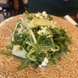 Arugula pear salad . Yum! - A salad featuring arugula, pear slices, cheese crumbles, and possibly other greens, served on a decorative plate.