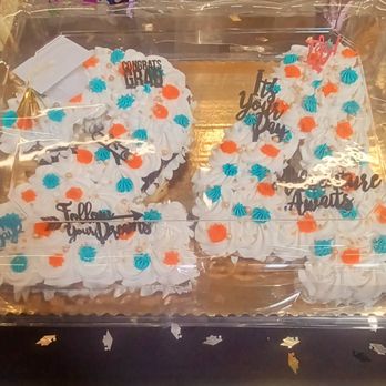 Albertsons - A tray of cupcakes arranged in the shape of the number 14, decorated with white frosting, blue and orange piped icing, and small pearl-like decorations. The cupcakes have toppers with messages such as 'Congrats Grab,' 'Let You Grow,' and 'Follow Your Dreams,' indicating a celebratory occasion like a birthday or milestone. The cupcakes are covered with a clear plastic lid for display or transport. - Grocery Near Me - El Paso, Texas