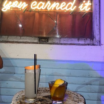 Half Step - a table with a drink and a neon sign - Cocktail Bars Near Me - Austin, Texas