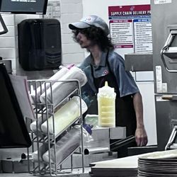 Domino's Pizza - Guy standing in front of the pizza, preparation area making pizza with his hair all over the place.