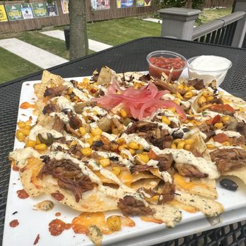 Shots - Pulled Pork Nachos topped with Corn-Black Bean salsa, drizzled with Chipotle Cilantro Lime creme, topped pickled onions - Summer Menu 2024 - Burgers Near Me - Grand Rapids, Michigan