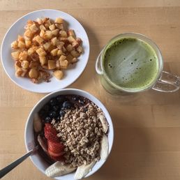 Hot matcha latte with an açaí bowl and potatoes.