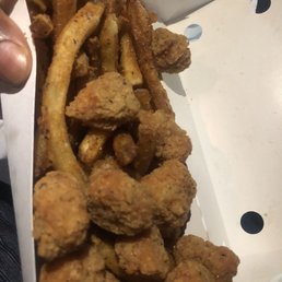 a person holding a box of fried food a person holding a box of fried food