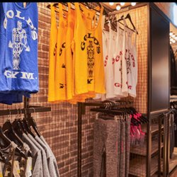 Colorful Gold's Gym tank tops, shirts, and workout apparel are displayed on clothing racks inside the pro shop at Gold's Gym ...
