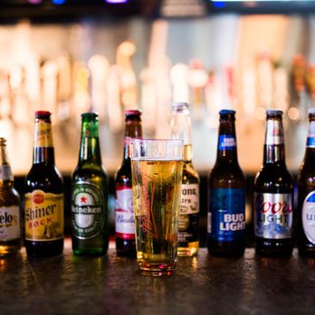 Jojos - a variety of beer bottles lined up on a bar counter - American Near Me - Yukon, Oklahoma