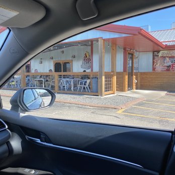 BP Smokehouse - The image shows the exterior of BP Smokehouse, a barbecue restaurant, as seen from inside a vehicle, including the side mirror and part of the dashboard. - Barbeque Near Me - Tomah, Wisconsin