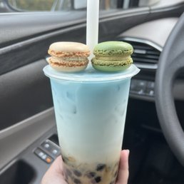 a hand holding a cup of iced tea with macarons on top a hand holding a cup of iced tea with macarons on top