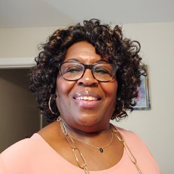 Hamrick's - Brown skinned curly hair and wearing glasses