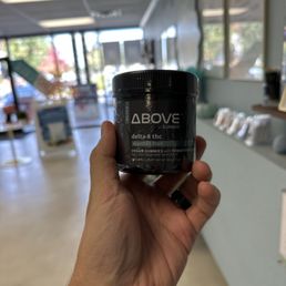 a hand holding a jar of cbd cream