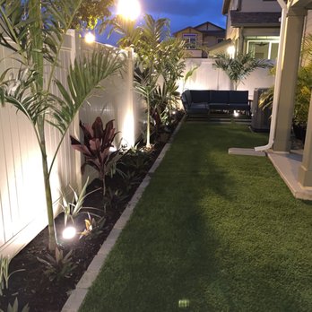 Hapa Landscaping - AFTER: Artificial grass, tropical plants planted, and brick border layer down (NIGHT VIEW) - Landscaping Near Me - Honolulu, Hawaii Hapa Landscaping - AFTER: Artificial grass, tropical plants planted, and brick border layer down (NIGHT VIEW) - Landscaping Near Me - Honolulu, Hawaii