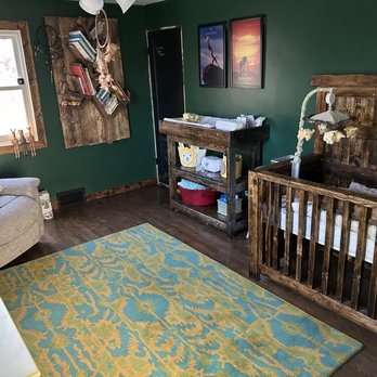 Oceanside Construction - a baby's room with a crib and rocking chair - General Contractors Near Me