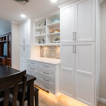 OZ General Contracting - White & wood 2-tone kitchen  L-shaped island, quartz everywhere, custom dining unit + sleek undercab & toe-kick lighting. #DreamKitchen - General Contractors Near Me - Bellmore, New York