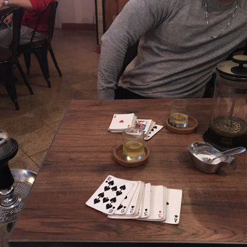 Majnoon Cafe - a man sitting at a table with playing cards - Hookah Bars Near Me - Ozone Park, New York