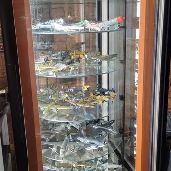 Chef Klaus' Bier Stube - Army planes - A glass display case contains multiple shelves of detailed model aircraft and military planes, arranged in a vertical display. - German Near Me - Frankfort, Illinois