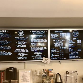 Velo Cafe - Menu - A large illuminated menu board at Velo Cafe in Cable, WI, lists offerings including salads, sandwiches, coffee, espresso, cold beverages, smoothies, and teas. - Juice Bars & Smoothies Near Me - Cable, Wisconsin