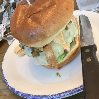 Windhill Pancake Parlor - A delicious sandwich - A sizable sandwich with melted cheese, lettuce, and various fillings on a plate, accompanied by a knife and a glass of water. - Breakfast & Brunch Near Me - McHenry, Illinois