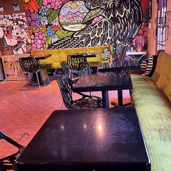 Blackbird Coffee House - Dining room - A cozy coffee shop features a vibrant mural with floral and abstract designs, along with various tables and chairs for patrons. - Coffee & Tea Near Me - Albuquerque, New Mexico