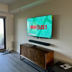 Samsung TV and soundbar mounted.  Low voltage cables are behind the wall and an outlet is directly behind the TV via a power kit.