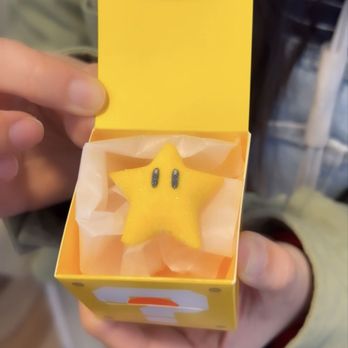 Power Up Cafe - a person holding a yellow box with a yellow star inside - Themed Cafes Near Me - Universal City, California