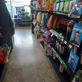 Turkey Hill - a grocery aisle - An aisle in a convenience store features snack bags on metal shelves, including chips and other snack foods, with Pepsi branded cups on the lower shelf. The store has large windows at the entrance, allowing natural light to illuminate the space and providing a view of the outside, including parked vehicles and signage. The floor is made of speckled material, and the store appears organized with various products displayed for customer selection. - Gas Stations Near Me - Gap, Pennsylvania