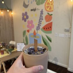 MiGi Cera Candles - Custom candle with coffee beans and some flower petals in front of their super cute mural!