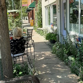 Kofe House - a woman sitting at a table under an umbrella - Coffee & Tea Near Me - Berthoud, Colorado Kofe House - a woman sitting at a table under an umbrella - Coffee & Tea Near Me - Berthoud, Colorado