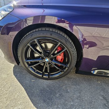 Chicago Ceramic Garrage - The image shows the front wheel of a purple BMW vehicle, featuring a black alloy rim and a red brake caliper, parked on a concrete surface. - Auto Customization Near Me - Chicago, Illinois