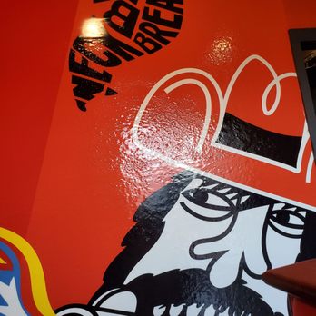 WingBucket - a red wall with a painting of a man smoking a cigarette - Chicken Wings Near Me - Arlington, Texas