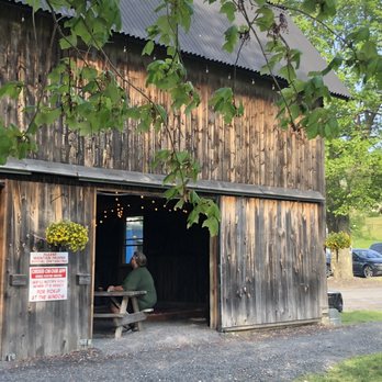 Orange County Distillery - a man sitting at a picnic table in front of a barn - Beer, Wine & Spirits Near Me - New Hampton, New York