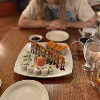 Dharma Blue - a woman sitting at a table with a plate of sushi - Sushi Bars Near Me - Pensacola, Florida Dharma Blue - a woman sitting at a table with a plate of sushi - Sushi Bars Near Me - Pensacola, Florida