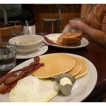 The Roost - The rooster, with bacon, eggs, and pancakes in the forefront, with French toast, eggs and bacon in the background, and splitting a half B&G - Breakfast & Brunch Near Me - Lawrence, Kansas The Roost - The rooster, with bacon, eggs, and pancakes in the forefront, with French toast, eggs and bacon in the background, and splitting a half B&G - Breakfast & Brunch Near Me - Lawrence, Kansas