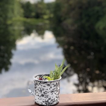 The Lost Kitchen - a potted plant on a railing overlooking a river - Salad Near Me - Freedom, Maine