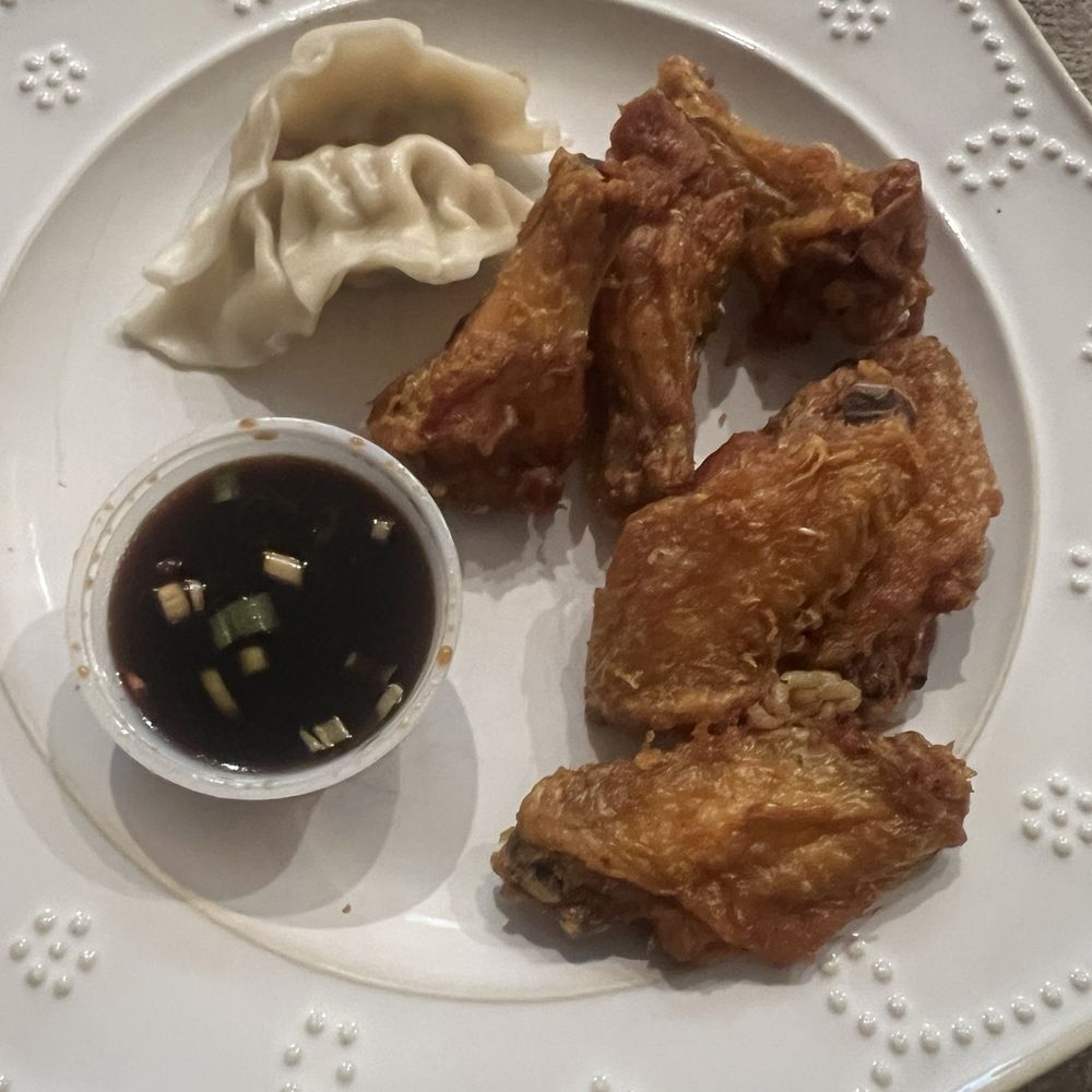 Chinese chicken wings and steamed dumplings with dipping sauce. Chinese chicken wings and steamed dumplings with dipping sauce.