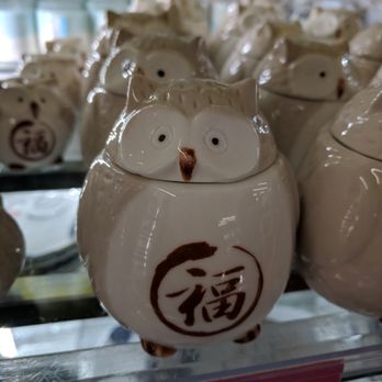 Daiso - A ceramic owl-shaped figurine with a glossy finish, featuring a Chinese character on its front. The figurine has detailed facial features resembling an owl and is part of a collection displayed on a store shelf. The background shows other similar items and store shelving, indicating it is for sale in a retail setting. - Department Stores Near Me - Concord, California