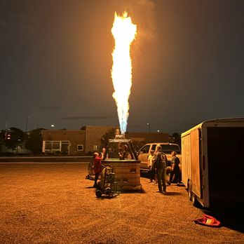 Fly Albuquerque - A hot air balloon is being inflated with a flame at night, with people gathered around in an open area. - Hot Air Balloons Near Me - Albuquerque, New Mexico