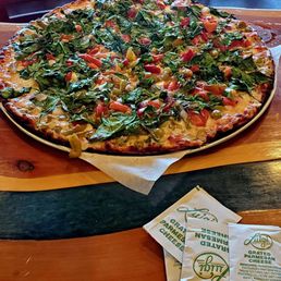 Spinach pizza with green olives and red onions.