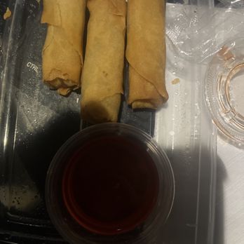 CoCo's Grill - Crispy spring rolls - Three fried spring rolls are arranged on a plastic tray, accompanied by a small cup of dark dipping sauce. - Japanese Near Me - Columbus, Ohio