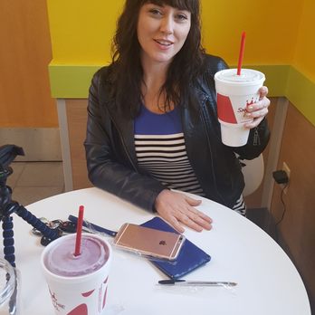 Smoothie King - a woman sitting at a table with a smoothie - Juice Bars & Smoothies Near Me - Memphis, Tennessee