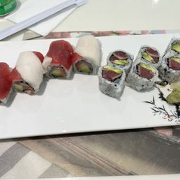 Pepper Tuna Avocado Rolls - A plate of assorted sushi rolls with tuna, avocado, and sashimi, served with wasabi and pickled ginger.
