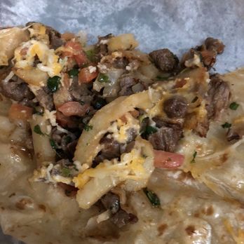 Maico - California Burrito, they forgot the sour cream and guacamole. : ( - A burrito with beef, cheese, and vegetables is shown partially eaten, with visible ingredients spilling out. - Mexican Near Me - Tucson, Arizona
