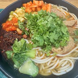 Spicy pork intestine noodle soup (with sauces, pickled veggies and garnishes added on)