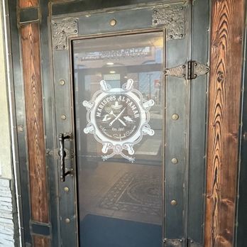 Mariscos Altamar - The door has a glass panel with the Mariscos Altamar logo, including text and decorative elements, framed by wood and metal accents. - Mexican Near Me - Albuquerque, New Mexico