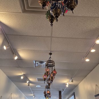 Grape Leaf Express - Multiple mosaic lanterns are suspended from the ceiling of an indoor room, with track lighting and artwork on the walls. - Mediterranean Near Me - Oregon, Ohio