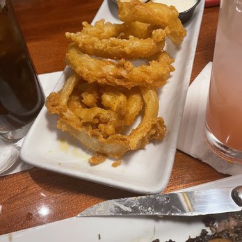 Copper Kettle - Onion rings - Fried onion rings served with two dipping sauces, one creamy and one possibly spicy, on a rectangular white plate at a restaurant. - Burgers Near Me - Dubuque, Iowa