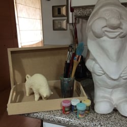 Un enano de yeso, junto a un toro, pinturas y pinceles que se venden en el lugar