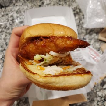 Shake Shack Las Colinas - a hand holding a chicken sandwich - Fast Food Near Me - Irving, Texas Shake Shack Las Colinas - a hand holding a chicken sandwich - Fast Food Near Me - Irving, Texas
