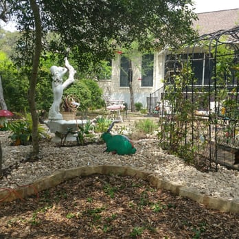 The Tree Guys - a garden with a birdhouse and a watering can - Tree Services Near Me - Buda, Texas