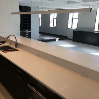 CPC Construction - a kitchen with white countertops and black cabinets - General Contractors Near Me
