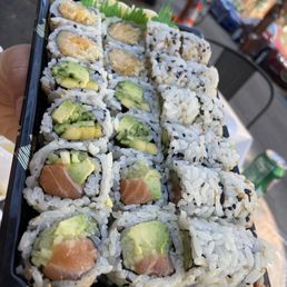 a hand holding a tray of nori sushi a hand holding a tray of nori sushi